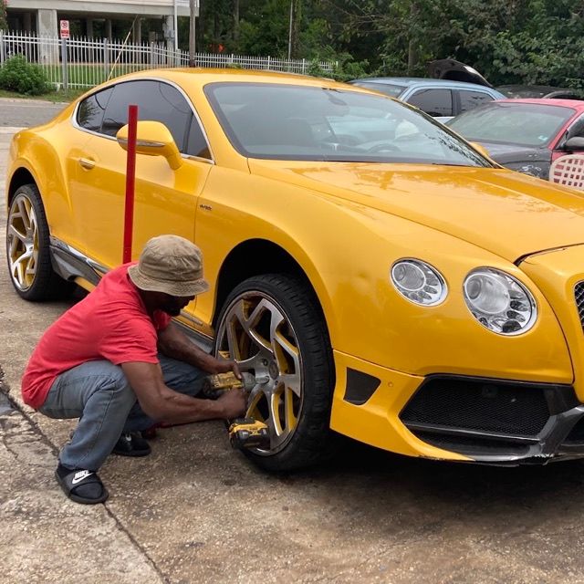 Zoe’s Mobile Tire Service mechanic using an impact wrench on a yellow Bentley’s wheel during an on-site tire job in Tallahassee